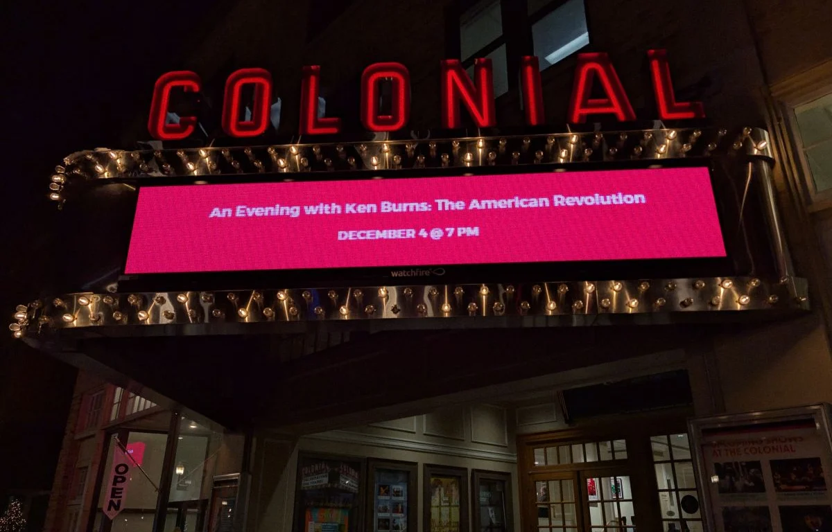 The Colonial Theatre marquee lit up at night in downtown Keene, NH, advertising an upcoming event.