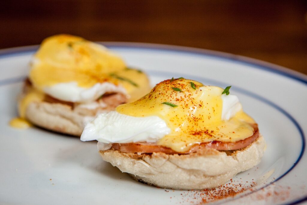 Two poached eggs Benedict topped with hollandaise sauce and chives, served on English muffins at the Inn of the Tartan Fox.