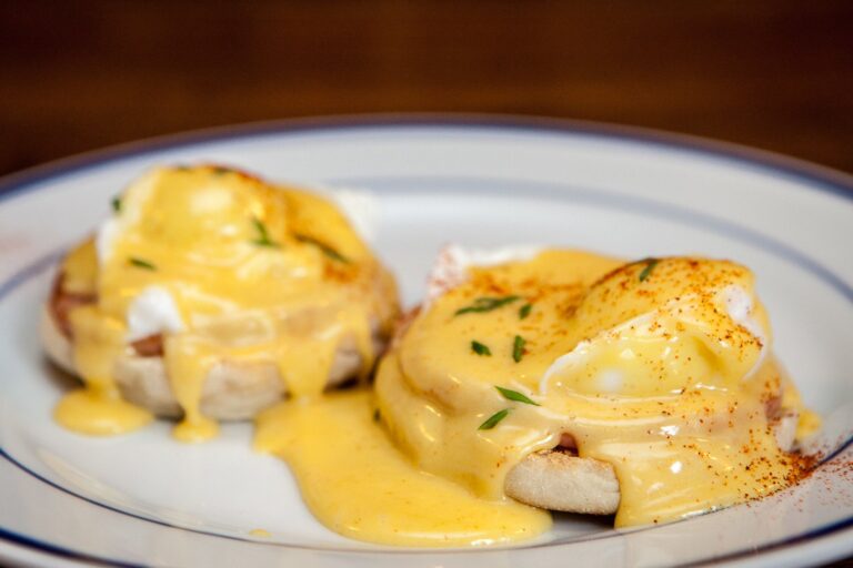 Close-up of two eggs Benedict with poached eggs, hollandaise, and chives, plated at the Inn of the Tartan Fox.
