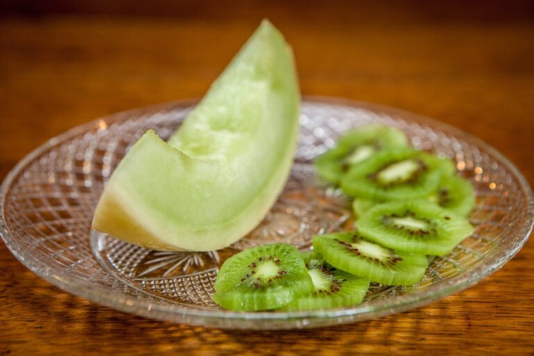 Sliced honeydew melon and kiwi arranged on a cut-glass plate, part of a breakfast course.